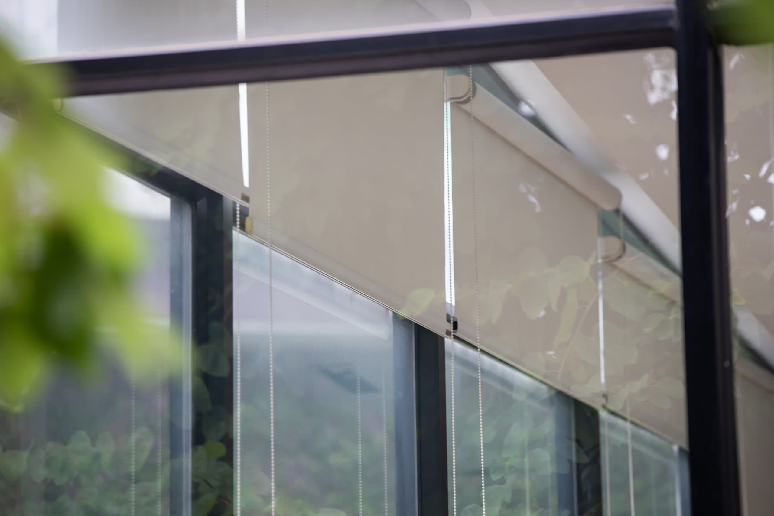 Roller shades installed across a living room window wall